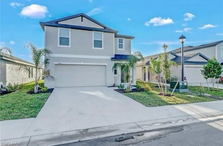 Traditional-style home with a garage, concrete driveway, a front lawn, and stucco siding
