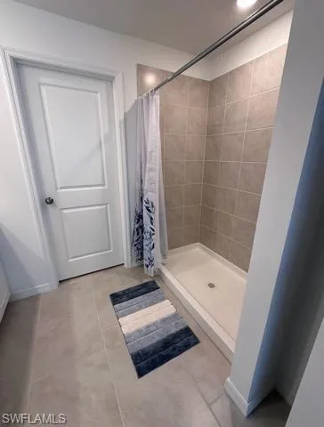 Full bath featuring a shower stall and light tile patterned floors