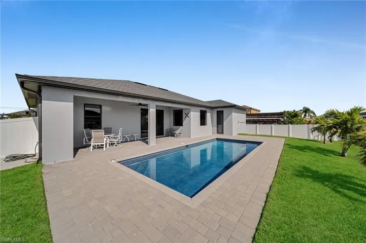 View of swimming pool with a patio, a fenced backyard, a lawn, and ceiling fan