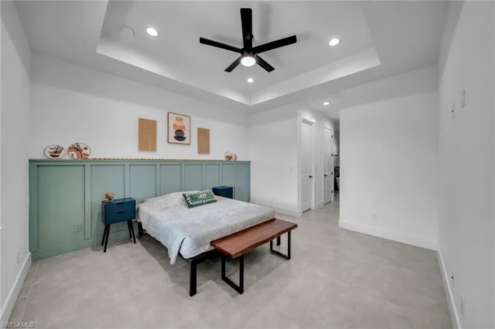 Bedroom featuring a raised ceiling, ceiling fan, baseboards, and recessed lighting