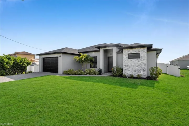 Prairie-style home featuring a front yard, a garage, fence, stucco siding, and driveway
