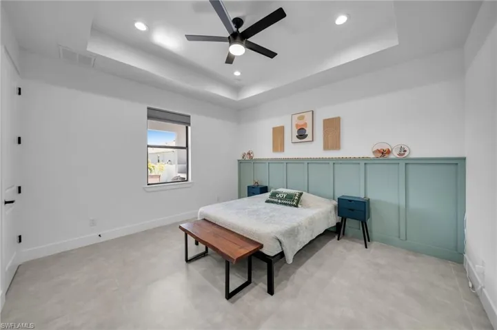 Bedroom featuring a raised ceiling, ceiling fan, visible vents, and recessed lighting