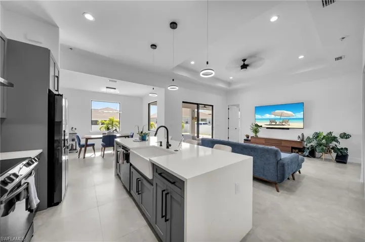 Kitchen featuring stainless steel appliances, recessed lighting, a tray ceiling, and a sink