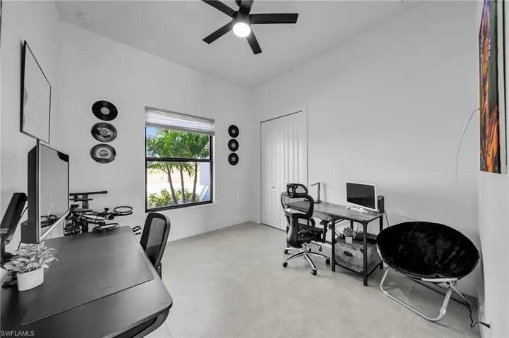 Home office with concrete flooring, ceiling fan, and baseboards
