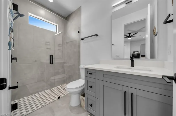 Bathroom with vanity, recessed lighting, a ceiling fan, toilet, and a shower stall