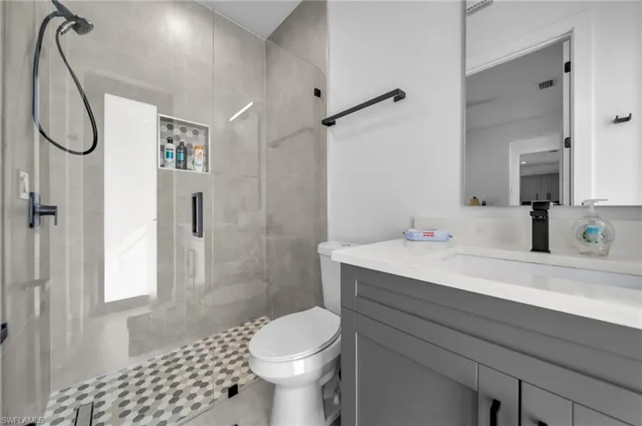 Full bathroom featuring a shower stall, vanity, visible vents, and toilet