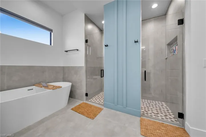 Full bath with a freestanding bath, recessed lighting, a stall shower, and tile walls