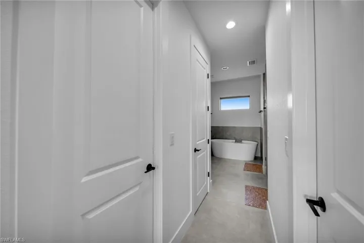 Corridor with recessed lighting, visible vents, and finished concrete flooring
