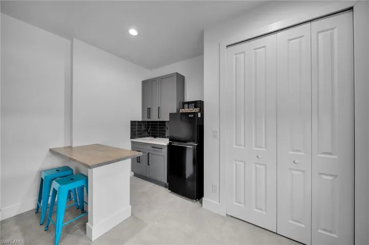 Kitchen with baseboards, freestanding refrigerator, recessed lighting, gray cabinetry, and backsplash