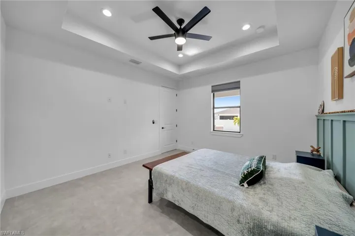 Bedroom with visible vents, baseboards, ceiling fan, a tray ceiling, and recessed lighting