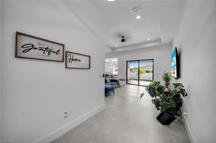 Hallway featuring light tile patterned floors, a tray ceiling, visible vents, recessed lighting, and baseboards