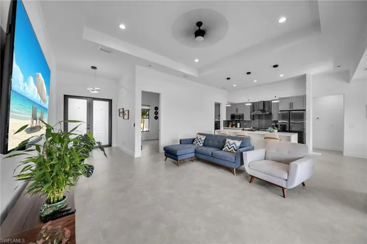 Living room with recessed lighting, concrete flooring, a tray ceiling, and baseboards