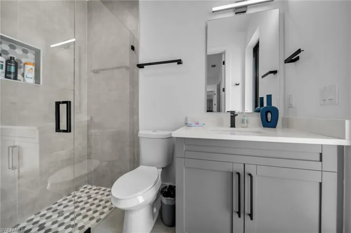 Bathroom featuring toilet, vanity, and a shower stall