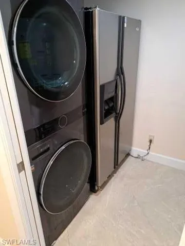 Laundry area with stacked washing and  maching dryer plus additional refrigerator