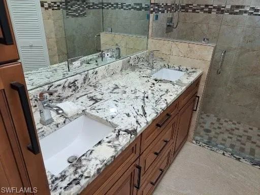 Master Bathroom featuring double sinks with granite counters and fully tiled shower with glass enclosure and swinging glass door.