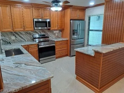 Kitchen with Granite Countertops backsplash, ceiling fan, appliances with stainless steel finishes, and sink