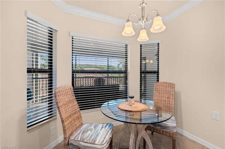 Tiled dining space with baseboards, an inviting chandelier, and crown molding