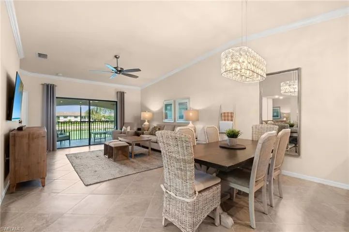 Dining area with ceiling fan with notable chandelier, crown molding, baseboards, and visible vents