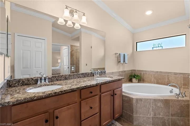 Full bath with crown molding, a sink, and a garden tub