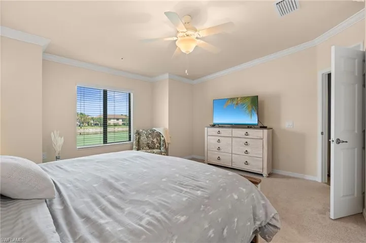 Bedroom featuring visible vents, baseboards, ornamental molding, a ceiling fan, and light carpet