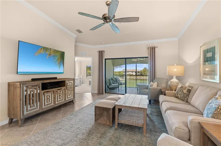 Tiled living area featuring baseboards, ornamental molding, visible vents, and a ceiling fan