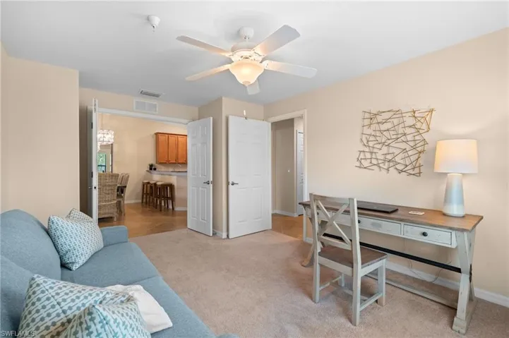 Home office with baseboards, visible vents, a ceiling fan, and light colored carpet