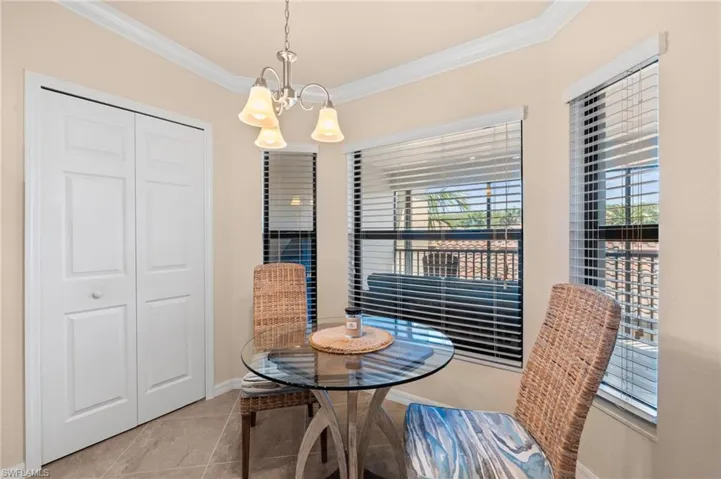 Tiled dining area featuring baseboards, a notable chandelier, and crown molding