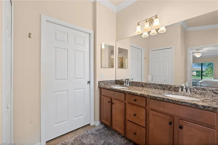 Bathroom with double vanity, a sink, and crown molding