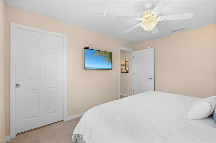 Bedroom with baseboards, ceiling fan, visible vents, and light colored carpet