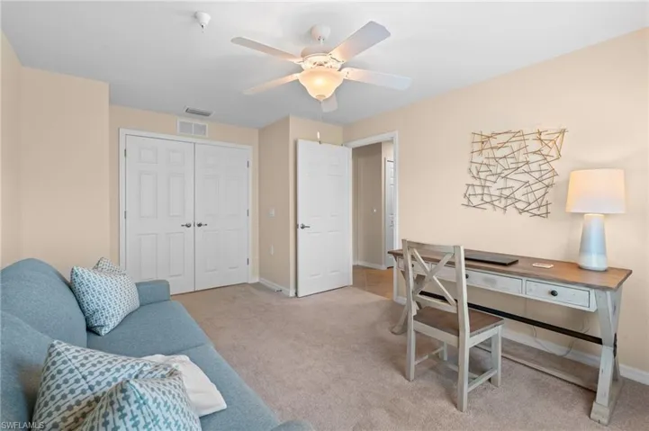 Office space featuring baseboards, visible vents, a ceiling fan, and light carpet
