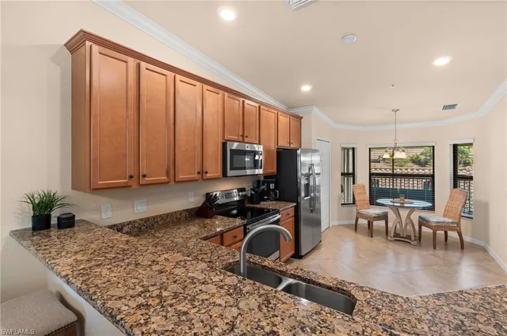 Kitchen featuring a sink, stainless steel appliances, crown molding, and brown cabinetry