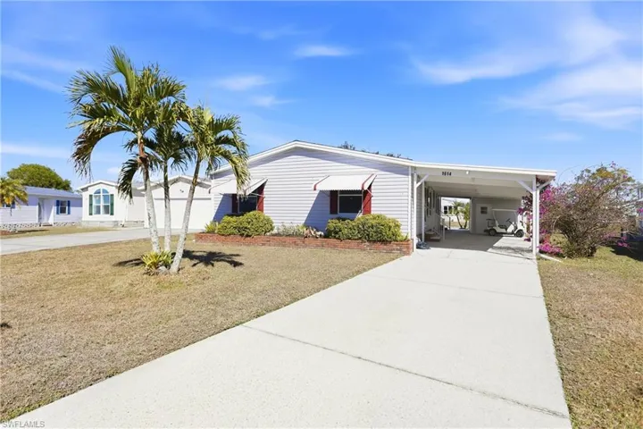 View of front of property with driveway, a front lawn, and a carport
