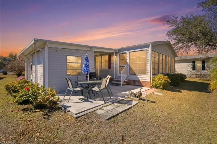 Back of house at dusk featuring a lawn, a patio area, and crawl space