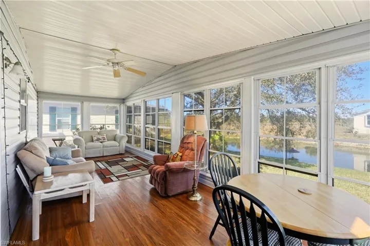 Sunroom with a ceiling fan, an outdoor living / dining area, vaulted ceiling, wood-type flooring, and a water view