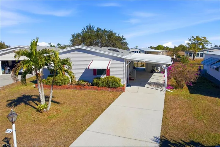 View of front facade with a front lawn, concrete driveway, and an attached carport