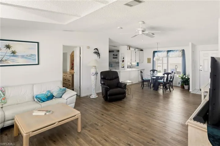 Living room with dark wood-style flooring and a ceiling fan