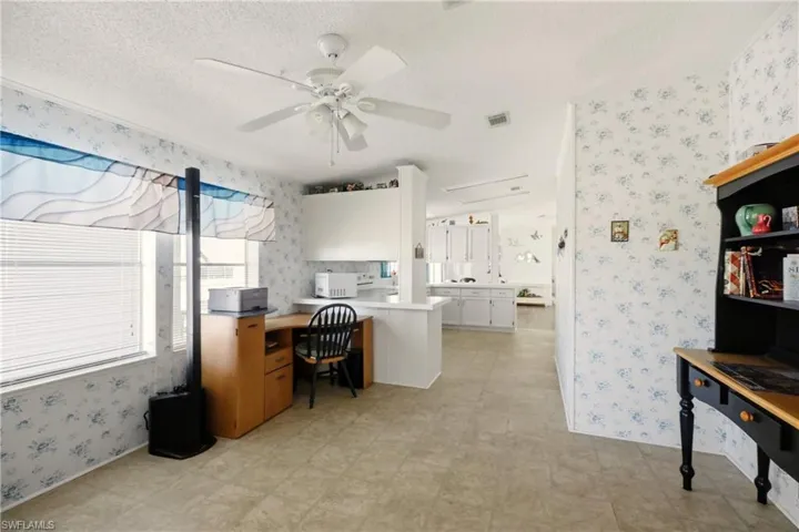 Home office with wallpapered walls, ceiling fan, and light floors
