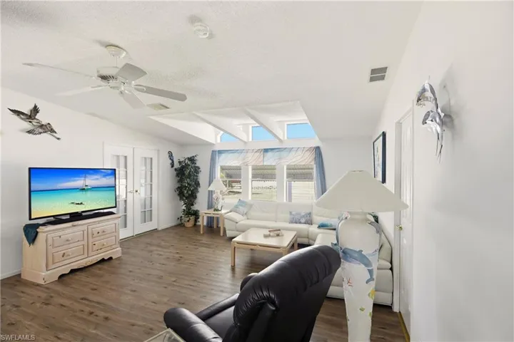 Living room featuring dark wood-type flooring, french doors, and ceiling fan