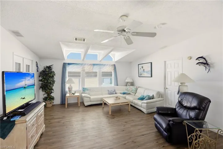 Living room featuring wood finished floors, a textured ceiling, and ceiling fan