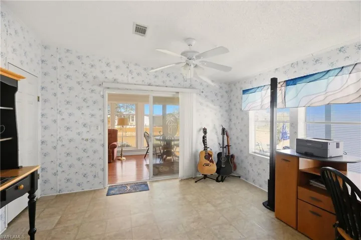 Office space featuring light flooring, a ceiling fan, a textured ceiling, and wallpapered walls