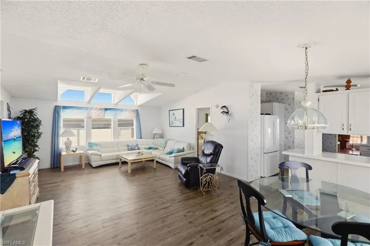 Living area with plenty of natural light, dark wood finished floors, ceiling fan, and a skylight