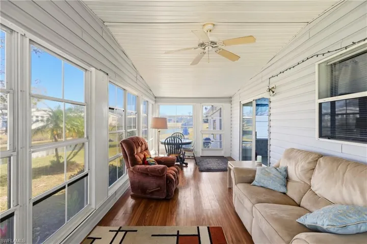 Sunroom / solarium with ceiling fan, hardwood / wood-style floors, an outdoor hangout area, wooden walls, and a vaulted wooden ceiling