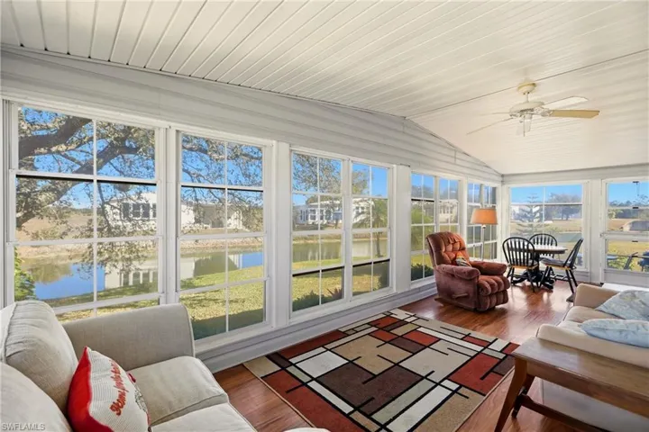 Sunroom with wood finished floors, lofted ceiling, and a water view