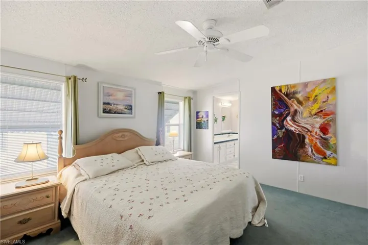 Bedroom featuring carpet, a textured ceiling, ceiling fan, and ensuite bathroom