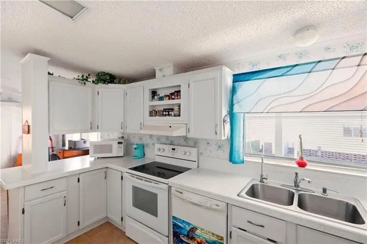 Kitchen featuring white cabinetry, white appliances, a textured ceiling, light countertops, and open shelves