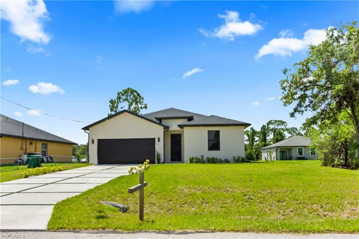 View of front of home featuring an attached garage, stucco siding, driveway, and a front lawn