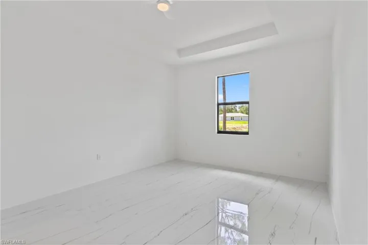 Unfurnished room featuring light marble finish flooring and a tray ceiling