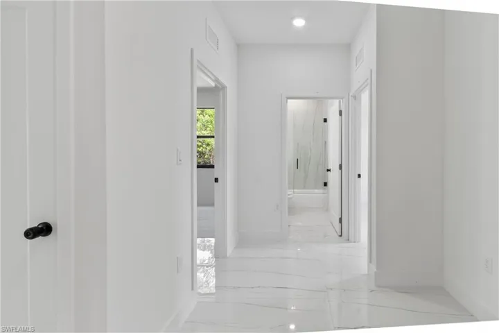 Corridor featuring baseboards and light marble finish flooring