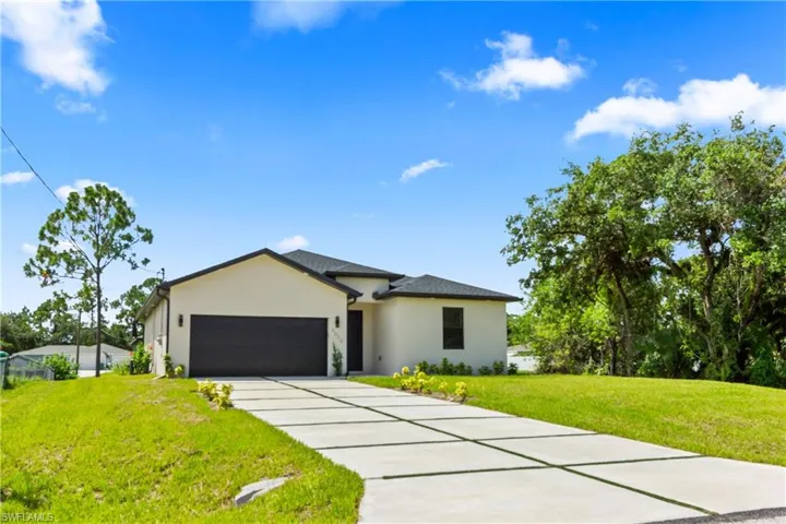 View of front of home with stucco siding, an attached garage, a front lawn, and concrete driveway