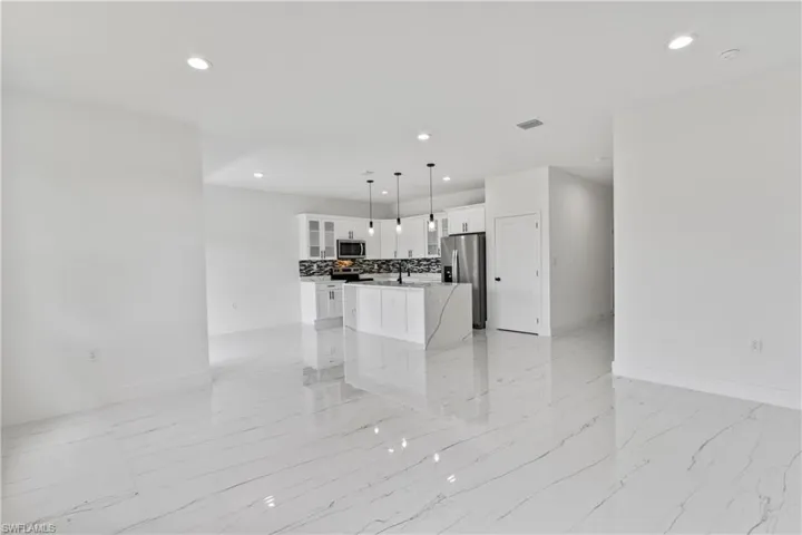 Kitchen with recessed lighting, a center island, light marble finish flooring, glass insert cabinets, and white cabinets